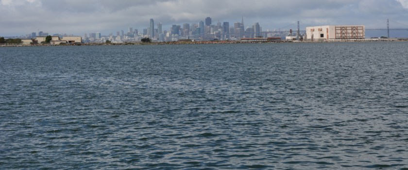 Seaplane Lagoon looking west, with blighted viewscape that will allowed to remain.  San Francisco is in background.  "Building 25" is the large building on the right that will be saved by a levee.