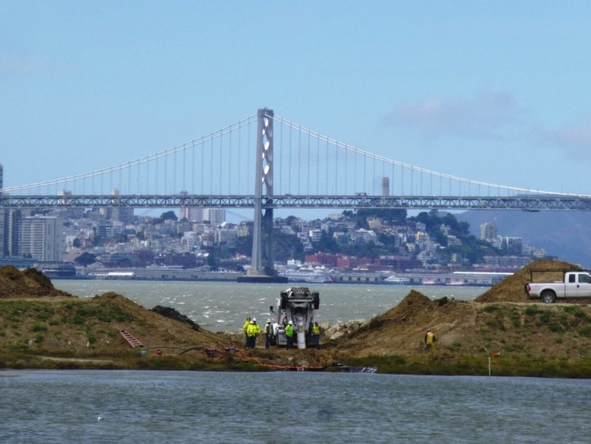 New culvert being installed.  North Pond of West Wetland at Alameda Point in foreground, San Francisco Bay in background.  Navy photo.