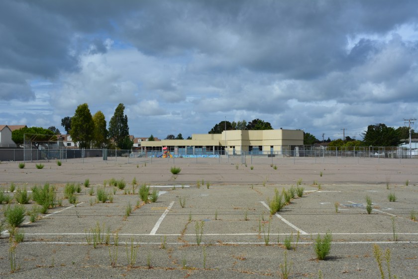 Vacant Island High School site on Singleton Avenue. Coast Guard housing is to the left. Singleton Avenue and vacant North Housing area is to the right. Woodstock Child Development Center is on the far side of the high school.