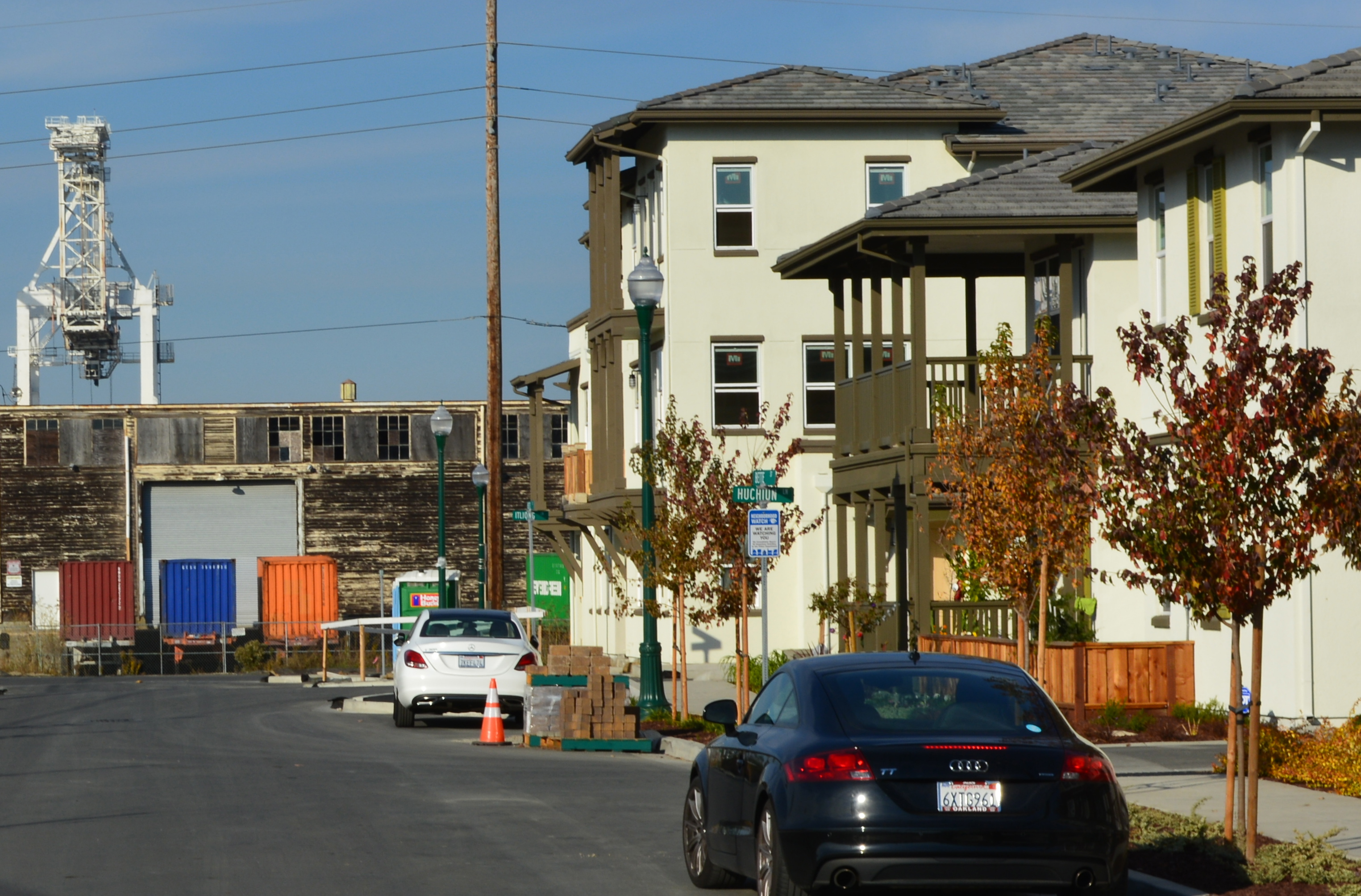 An old warehouse used for the Navy's former Fleet Industrial Supply Center and a crane at the Port of Oakland provide a backdrop for condominiums nearing completion on Bette Street at Alameda Landing.